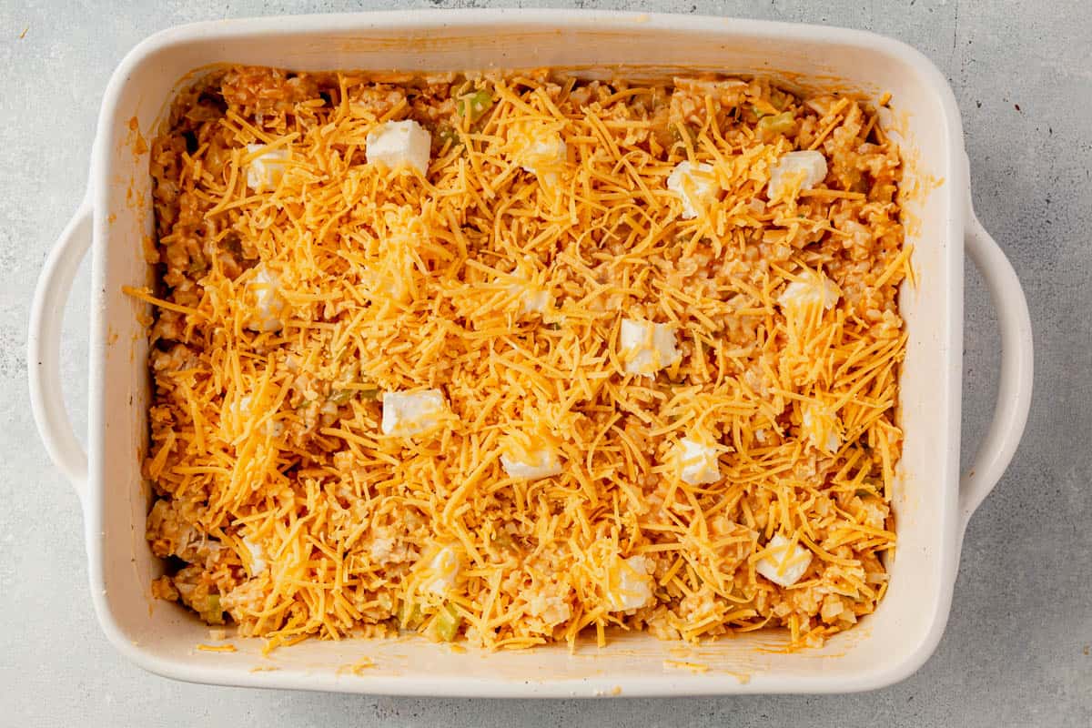 unbaked buffalo chicken casserole with shredded cheese on a counter