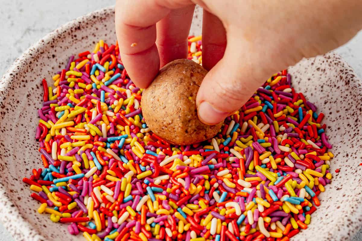 dipping a protein ball into sprinkles