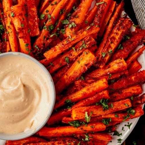 a plate of crispy carrot fries with parmesan cheese and spicy mayo sauce