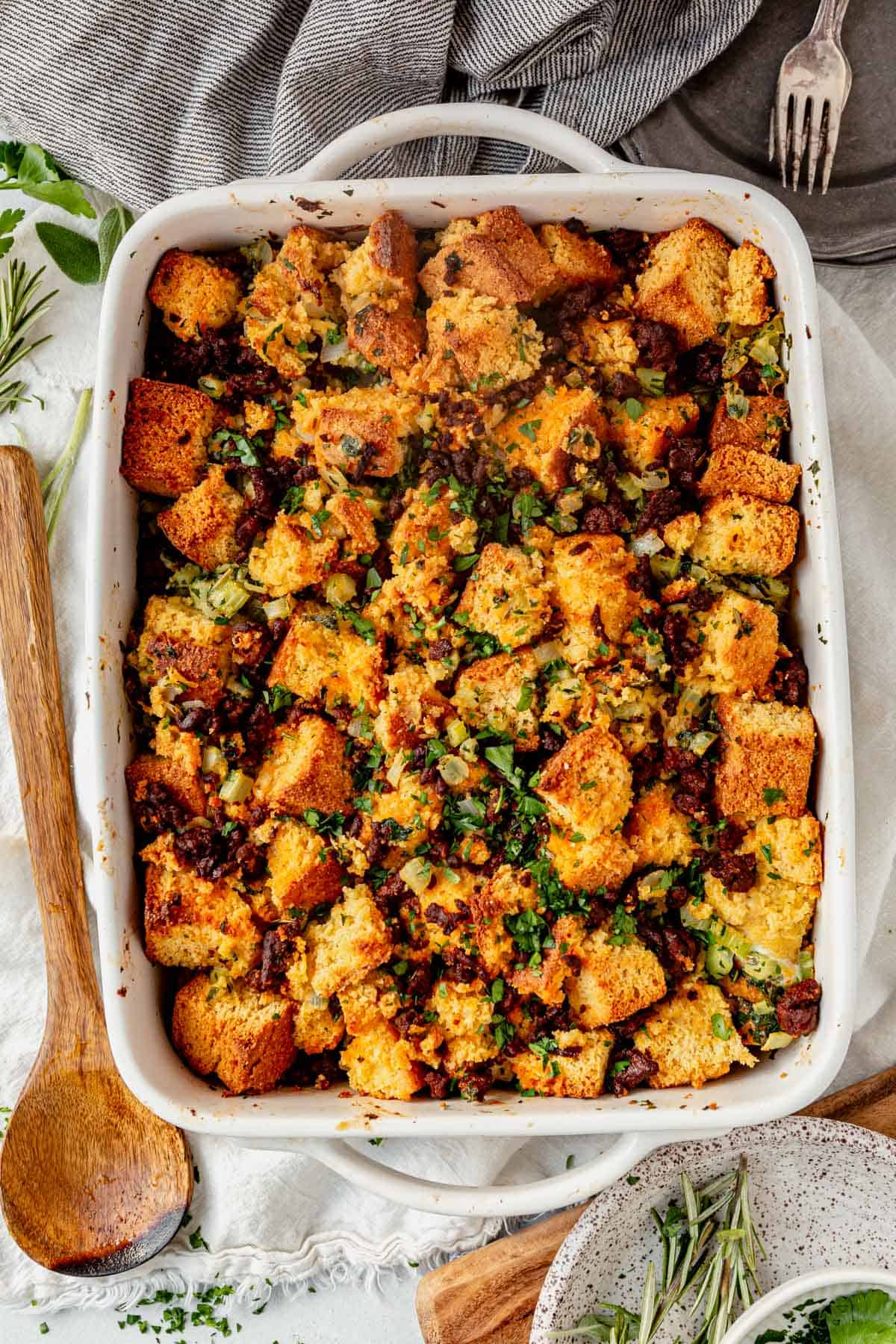 chorizo cornbread stuffing in a casserole dish with a wooden serving spoon