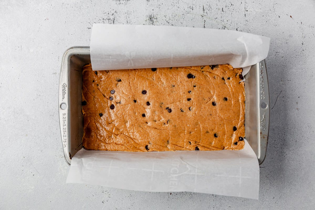 cookie dough protein bars in a parchment lined pan