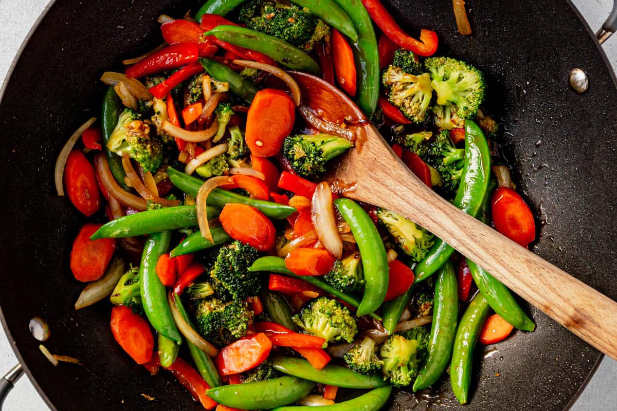 stir fry vegetables coated in sauce in a wok