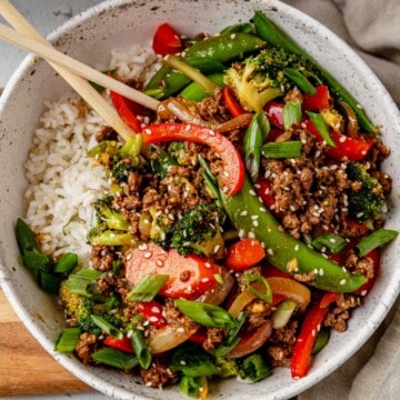 white rice and ground beef stir fry in a bowl with chopsticks