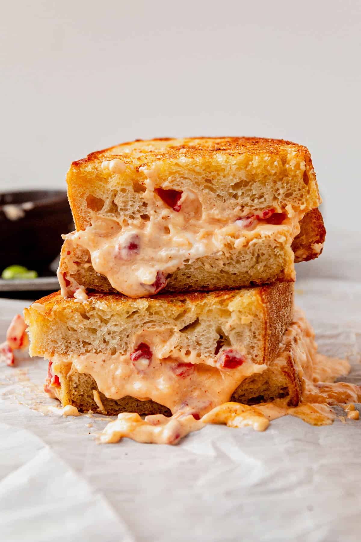 two halves of a pimento grilled cheese stacked on parchment paper