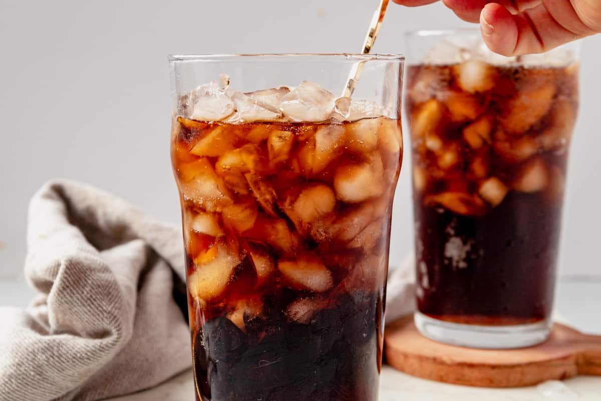 stirring rum, ice, and root beer in a glass