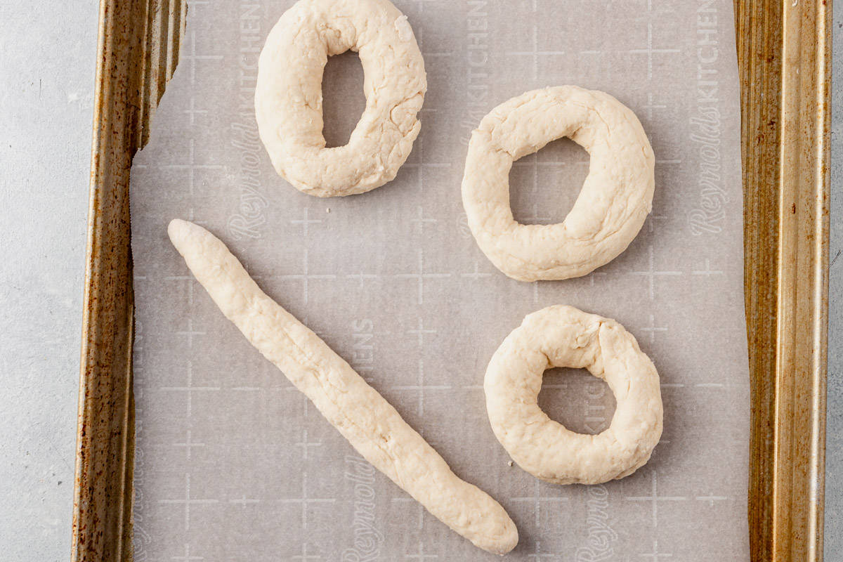 3 pieces of dough shaped into bagels and one rolled into a rope