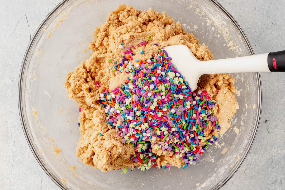 edible sugar cookie dough in a mixing bowl with rainbow sprinkles