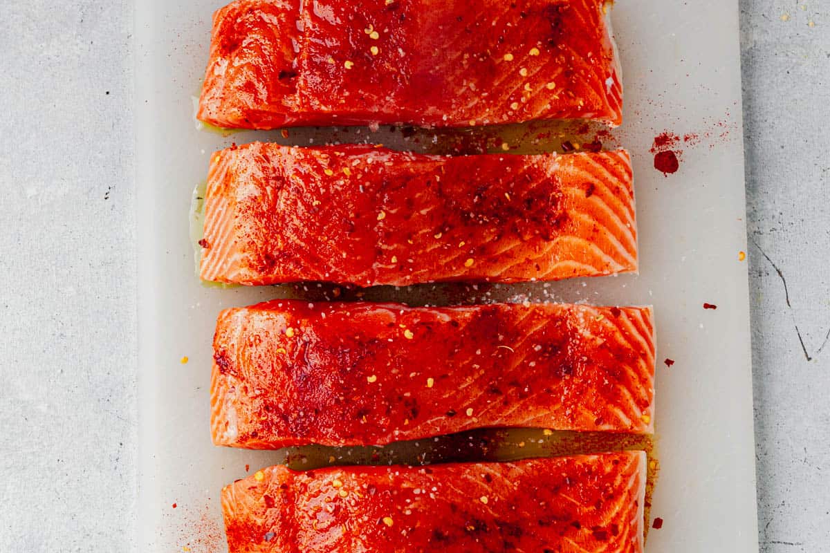 seasoned raw salmon filets on a cutting board