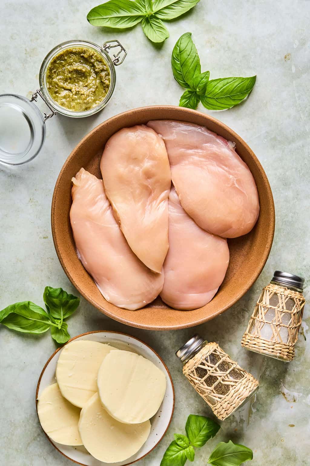 chicken breast, pesto, and fresh mozzarella cheese on a counter.