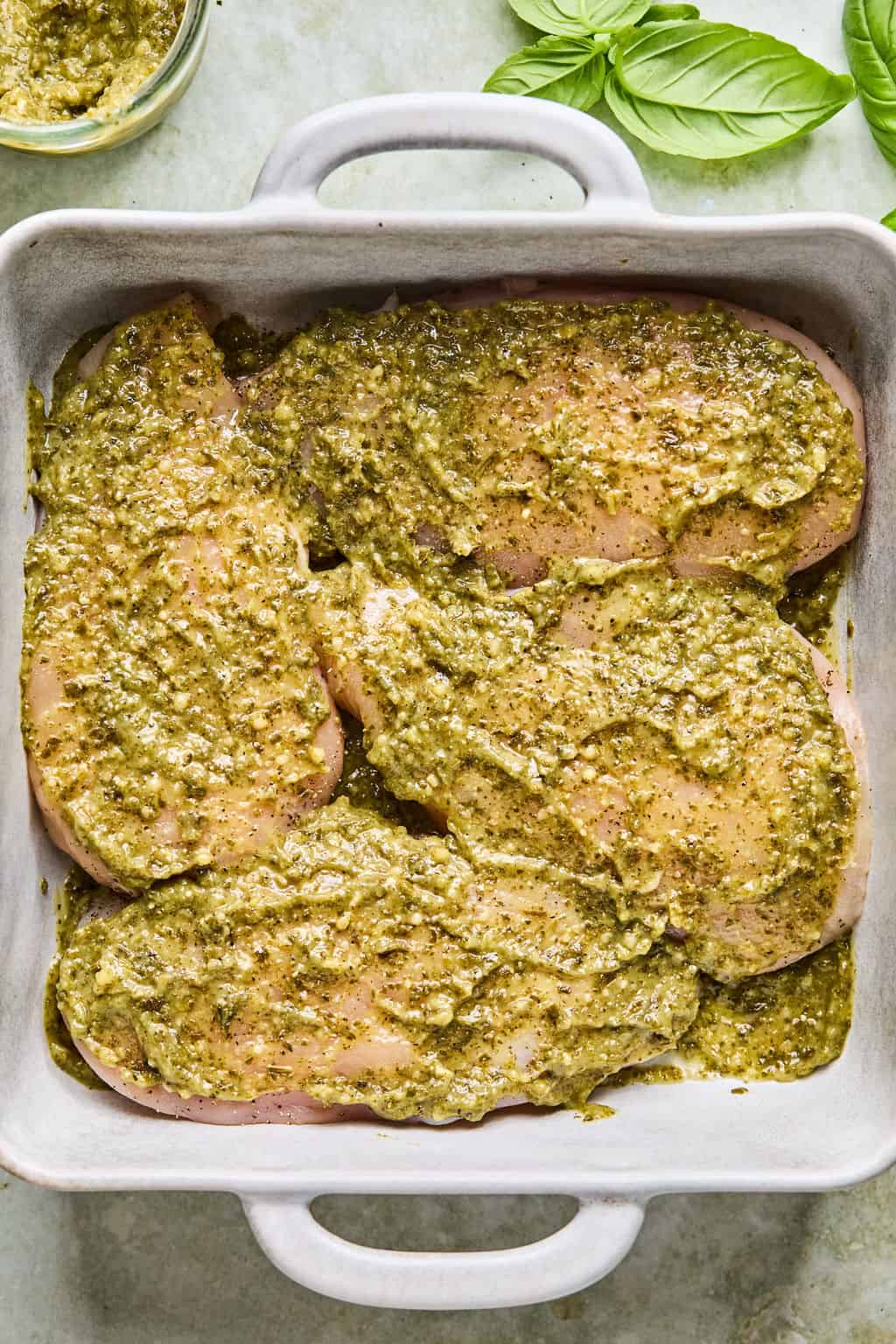 raw chicken breasts coated in pesto sauce.