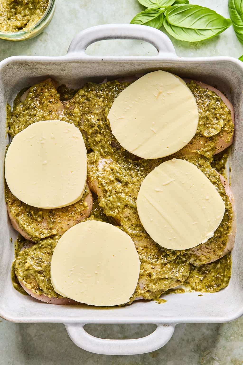pesto chicken topped with a slice of fresh mozzarella cheese before baking.