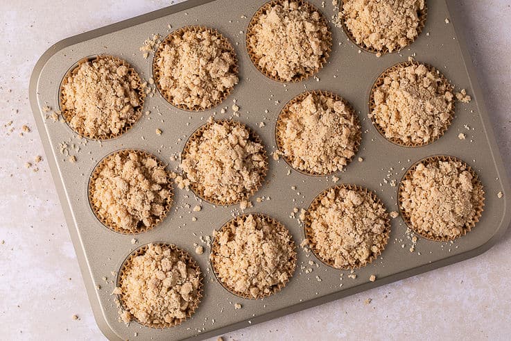 coffee cake muffin batter in muffin tin topped with streusel.