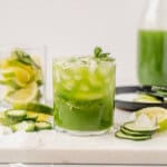 cucumber margarita in a rocks glass with crushed ice, fresh cucumber slices, and garnished with mint.