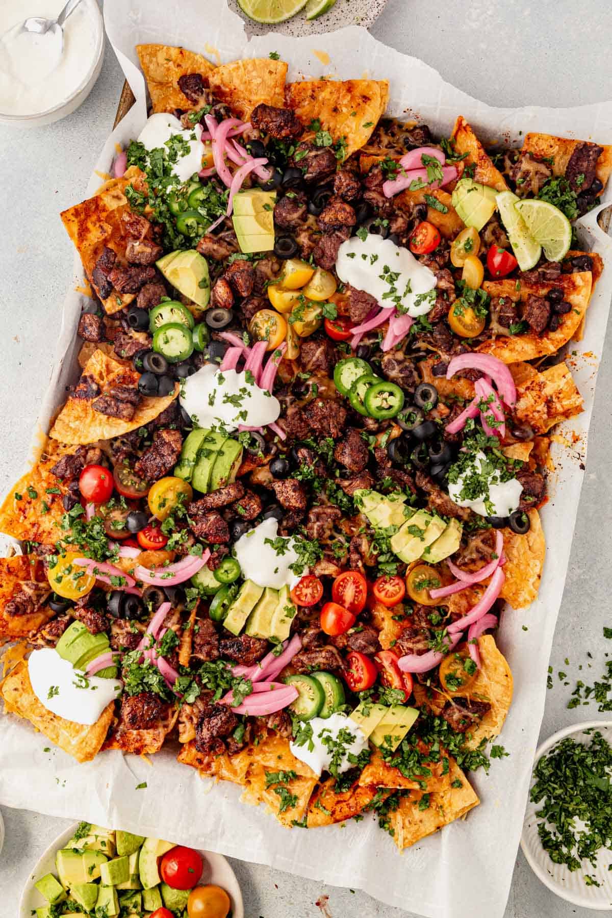 steak nachos on a sheet pan loaded with mexican toppings