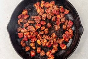 steak cubes searing in a cast iron skillet