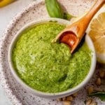 a wooden spoon in a bowl of homemade basil pesto