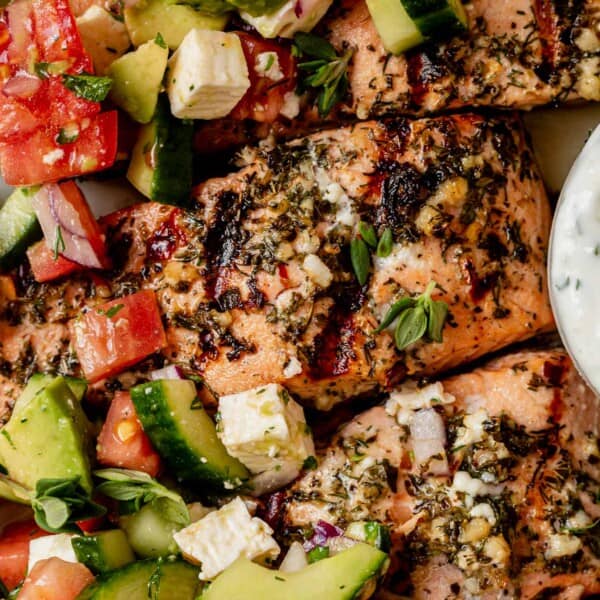 greek salmon on a plate with greek salad and tzatziki