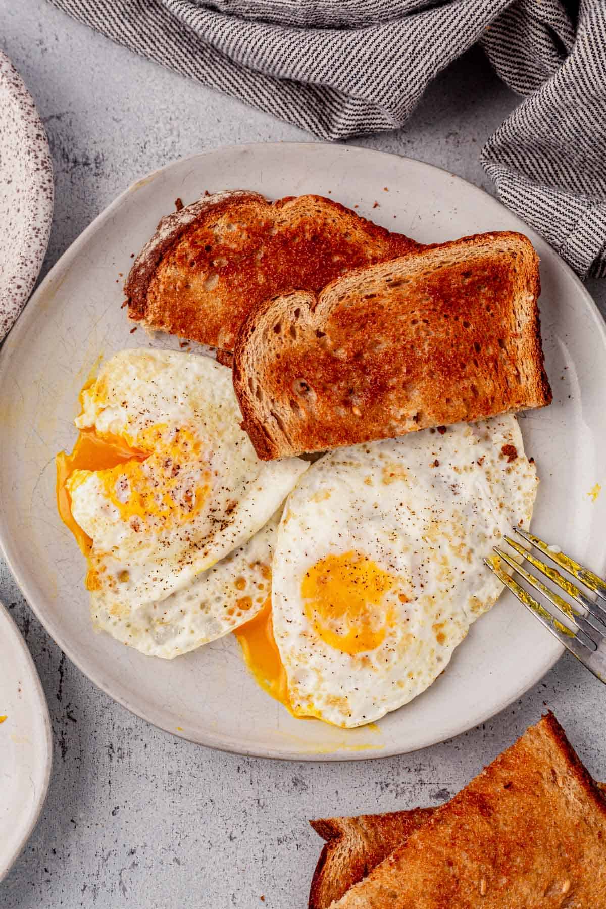 two over-medium eggs on a plate with buttered toast
