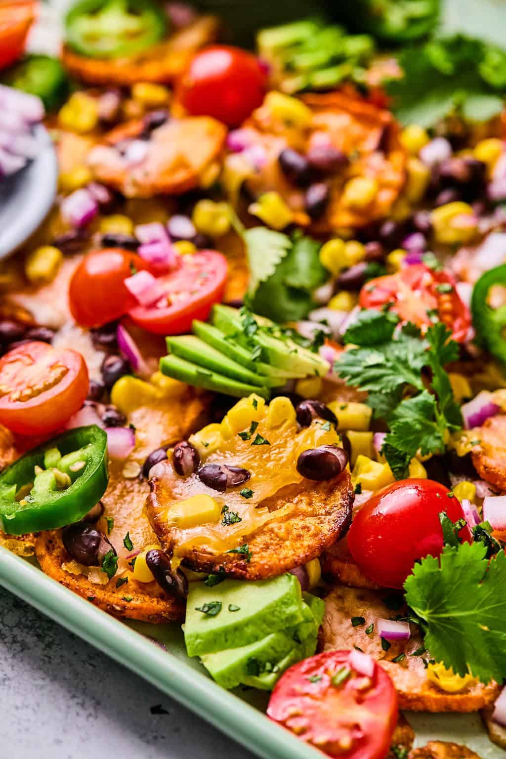 sweet potato nachos topped with avocado, jalapeno, and tomato.