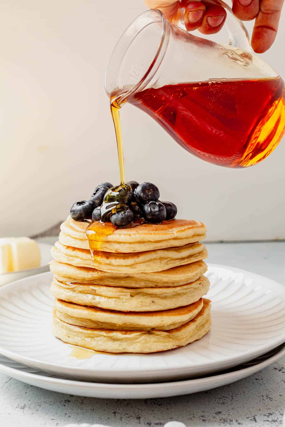 pouring maple syrup on top of cottage cheese pancakes