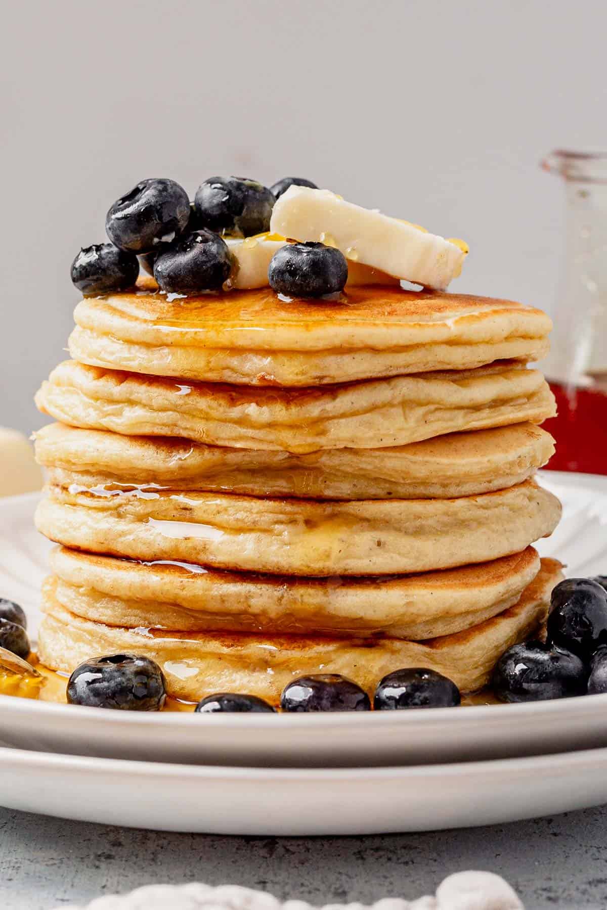 a stack of cottage cheese pancakes with blueberries, butter, and syrup