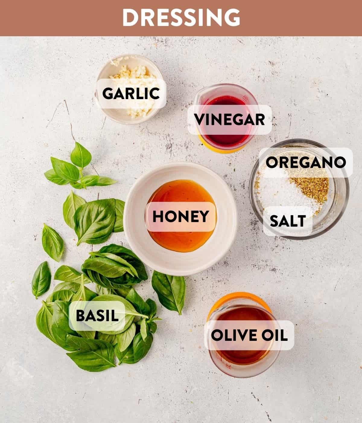 olive oil, basil, oregano, honey, garlic, and vinegar on a counter