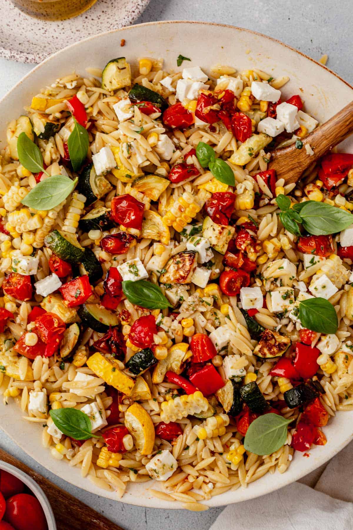 roasted vegetable pasta salad in a bowl with a serving spoon