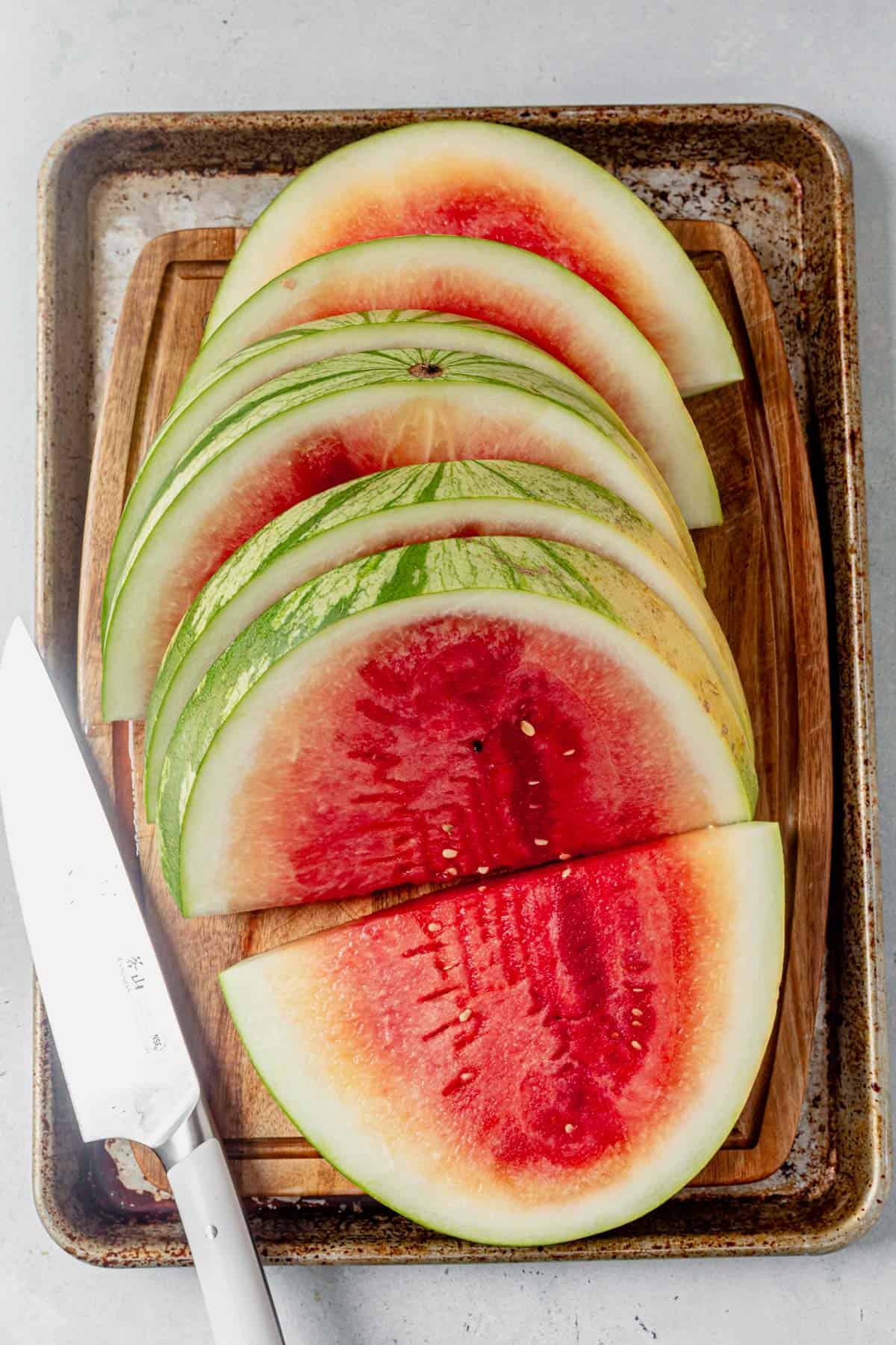 sliced watermelon cut into half moons on a cutting board