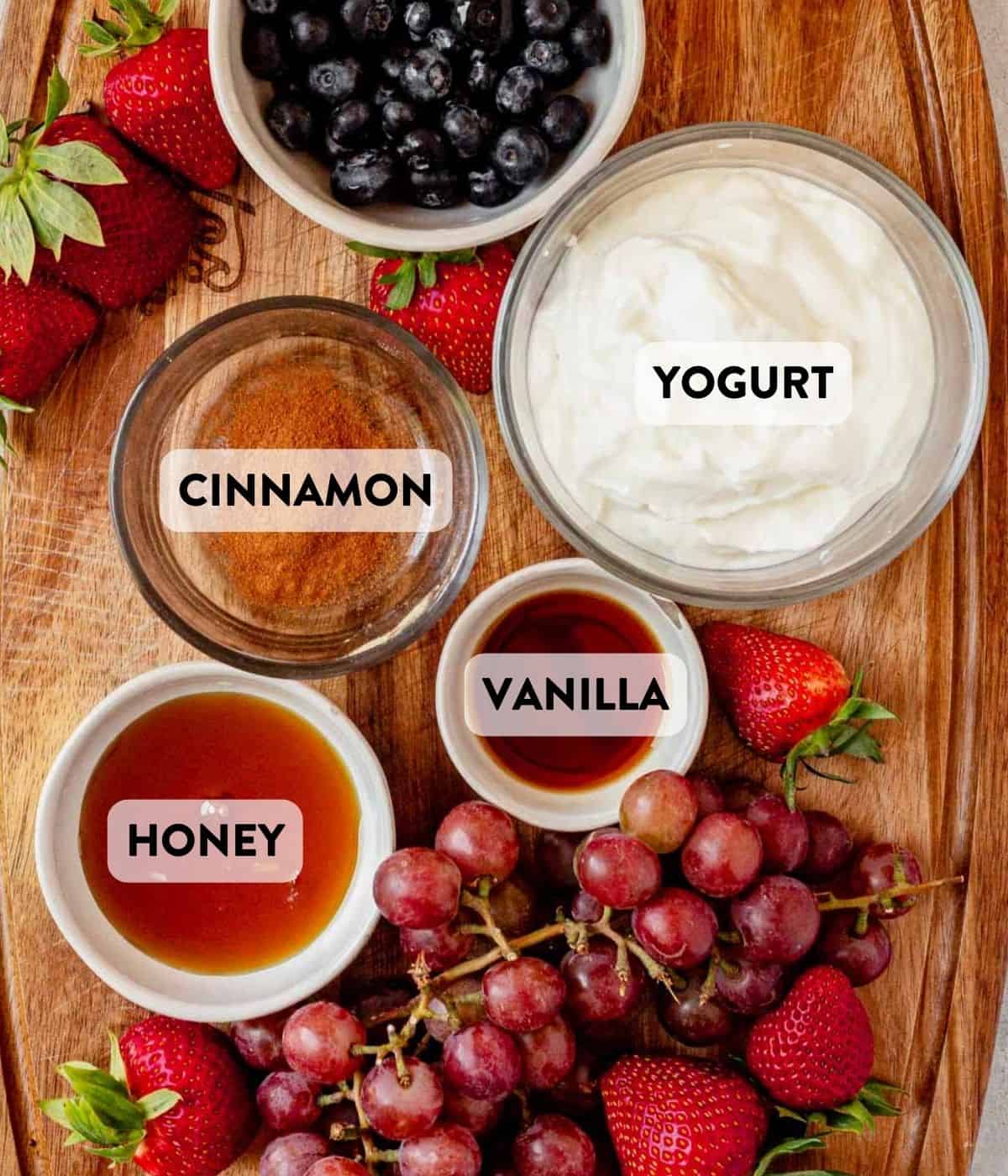 yogurt, cinnamon, honey, vanilla, and fruit on a cutting board