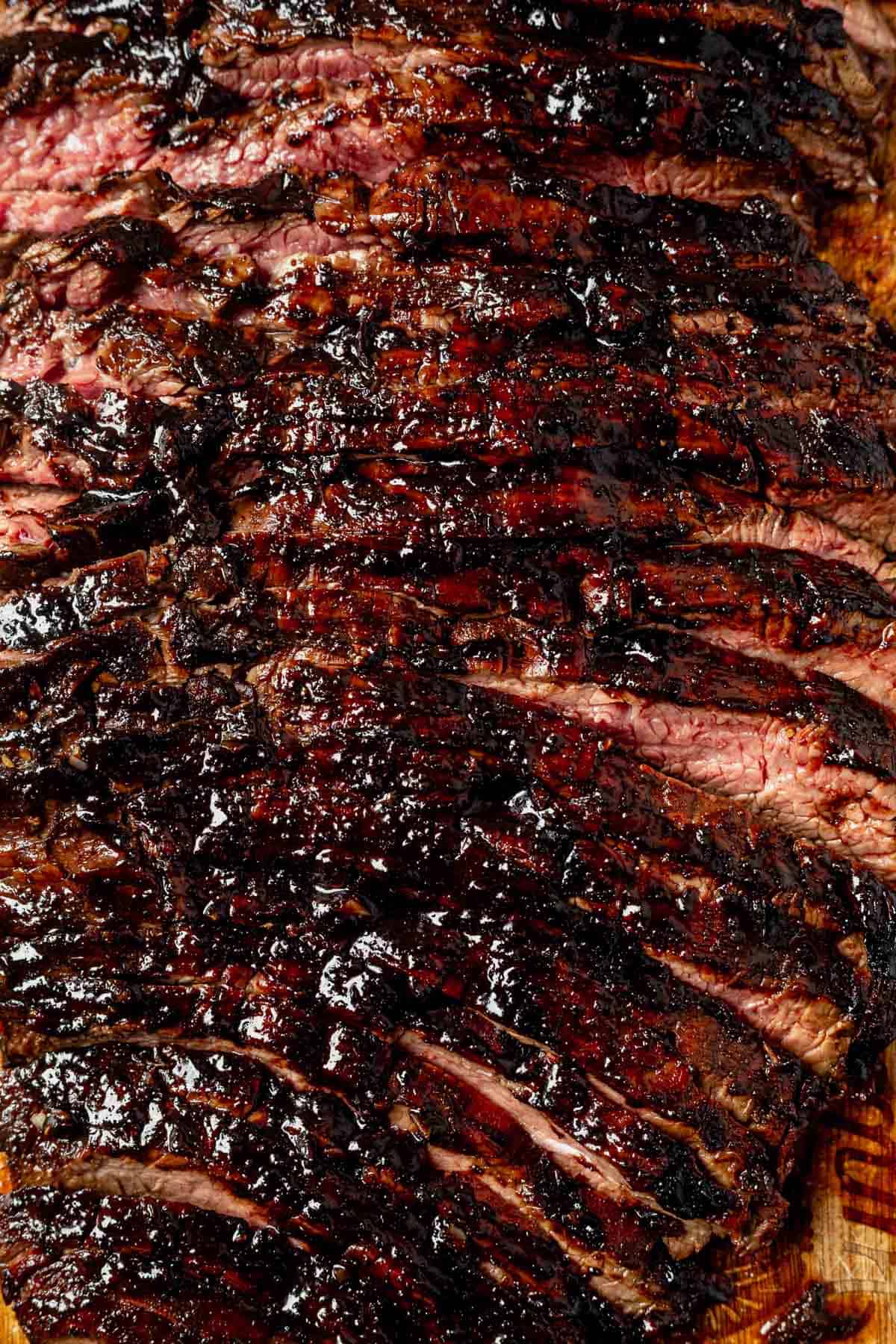 grilled balsamic flank steak sliced on a cutting board with balsamic glaze