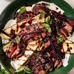 balsamic flank steak in a serving bowl with zucchini and balsamic glaze