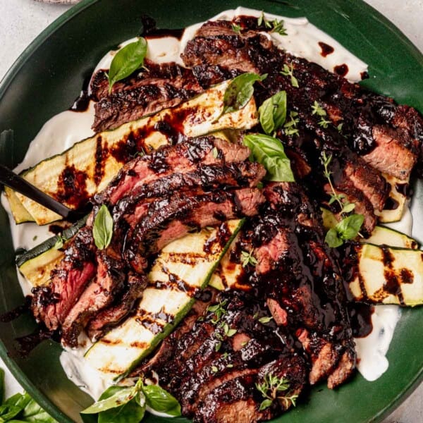 balsamic flank steak in a serving bowl with zucchini and balsamic glaze