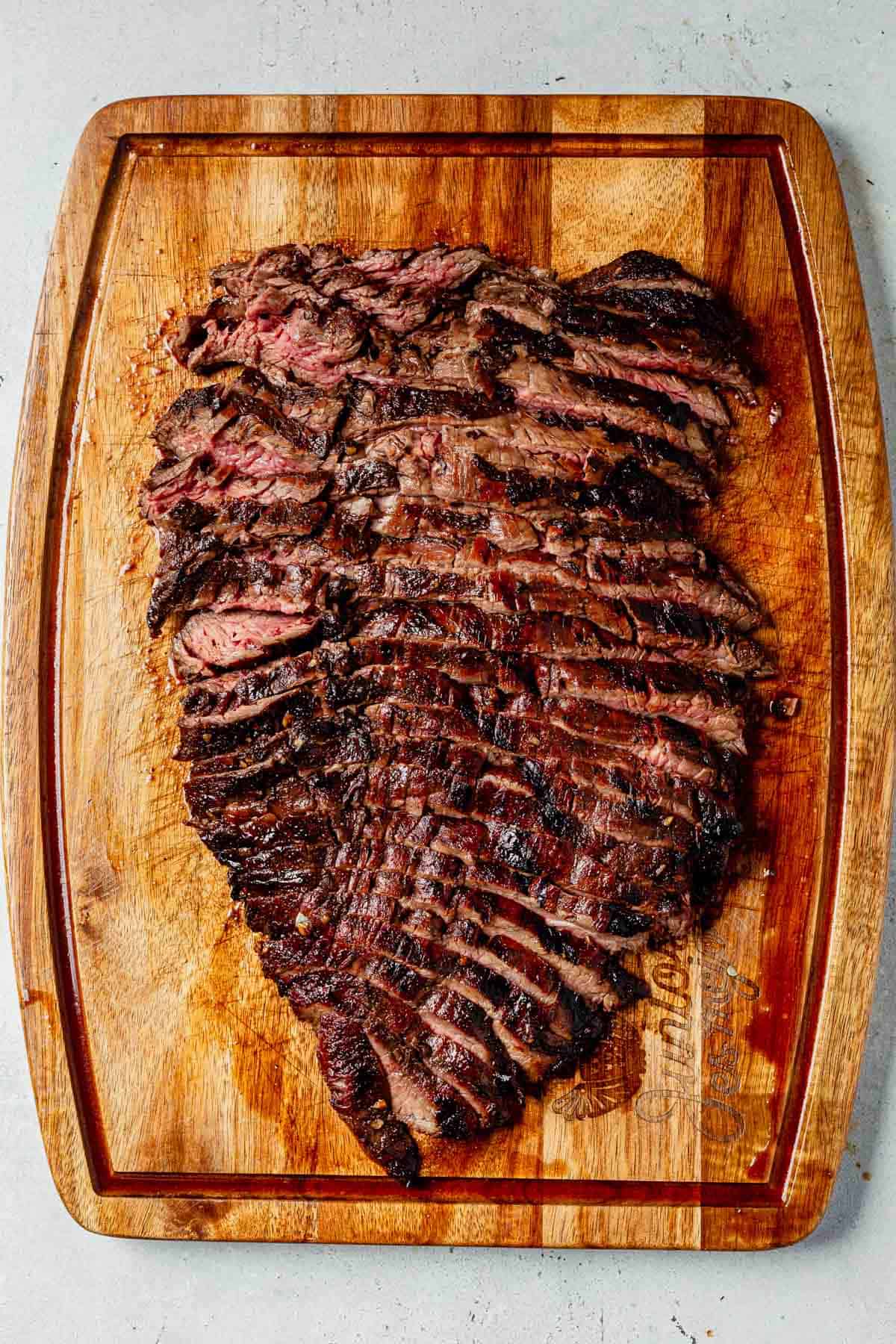 thinly sliced balsamic flank steak on a cutting board