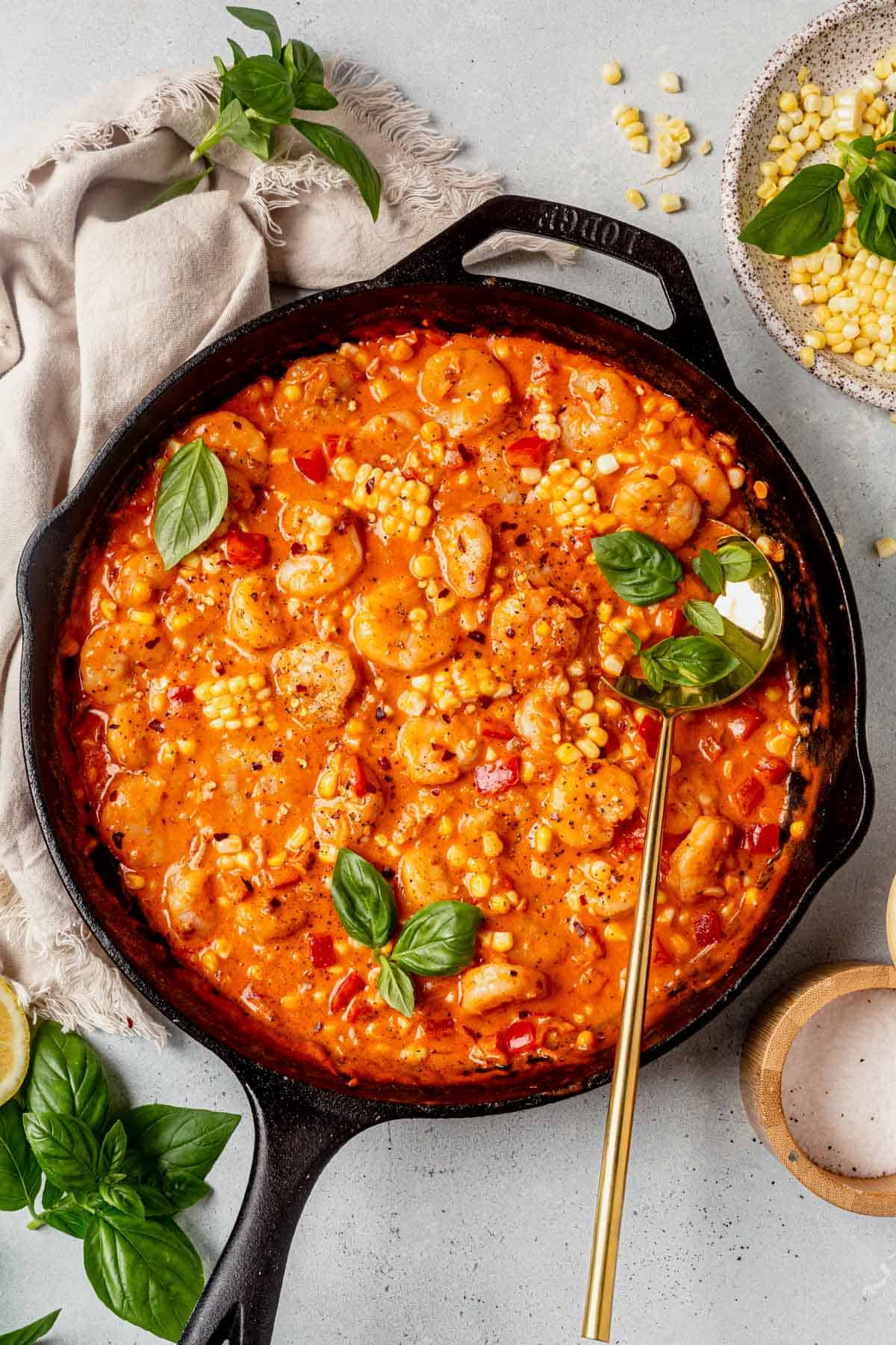 creamy coconut shrimp in a skillet with a serving spoon.