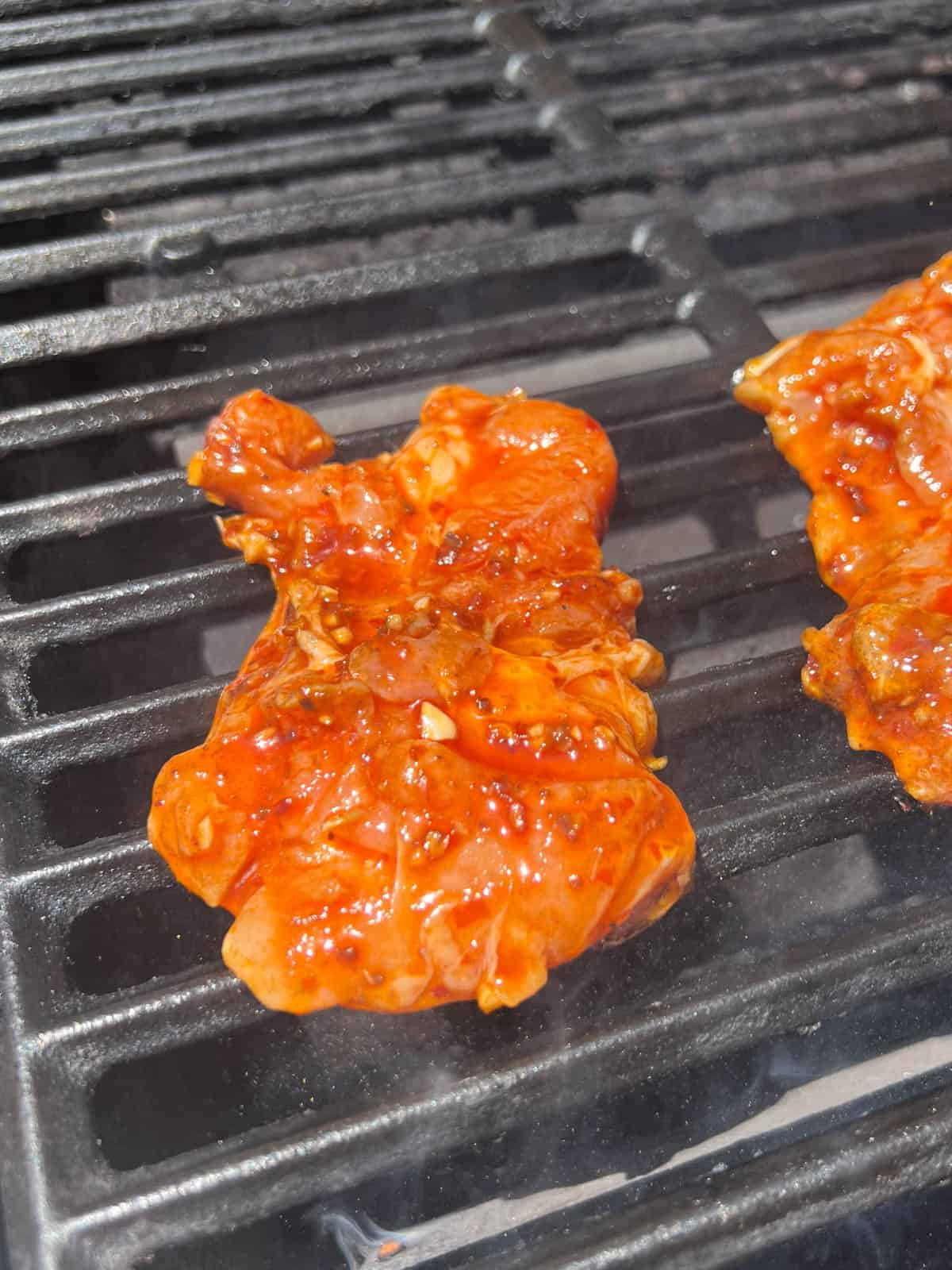 harissa chicken thighs cooking on a grill