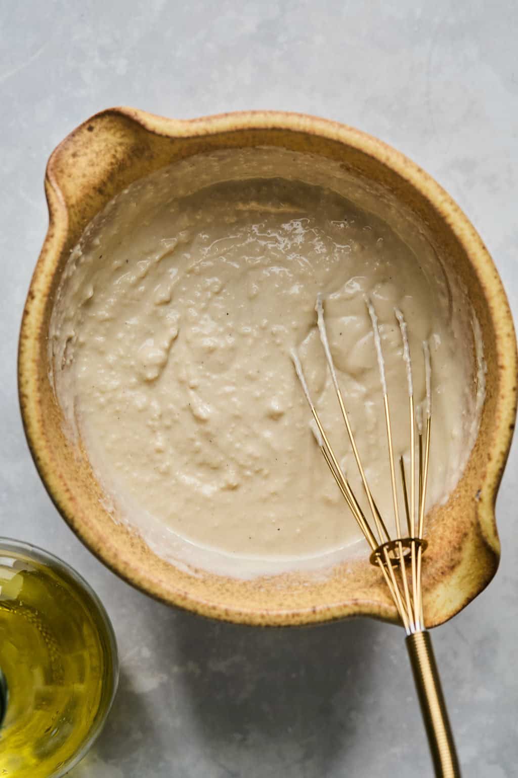 whisking homemade caesar dressing in a bowl.