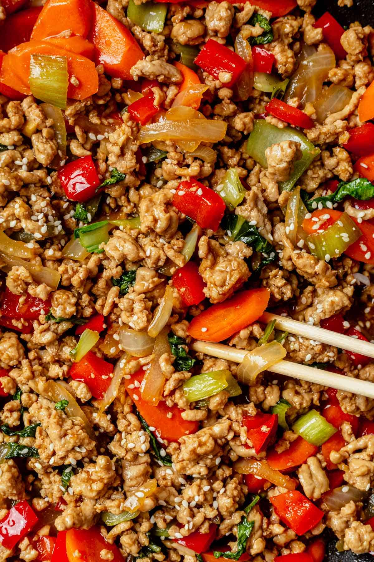 ground pork stir fry in a skillet with chop sticks.