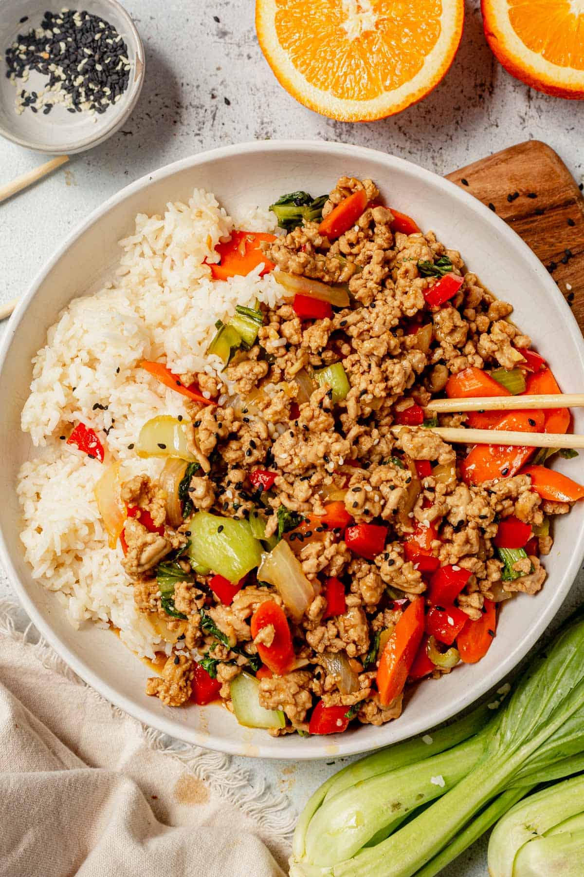 ground pork stir fry in a bowl with rice and chopsticks.