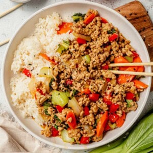 ground pork stir fry in a bowl with rice and chopsticks.