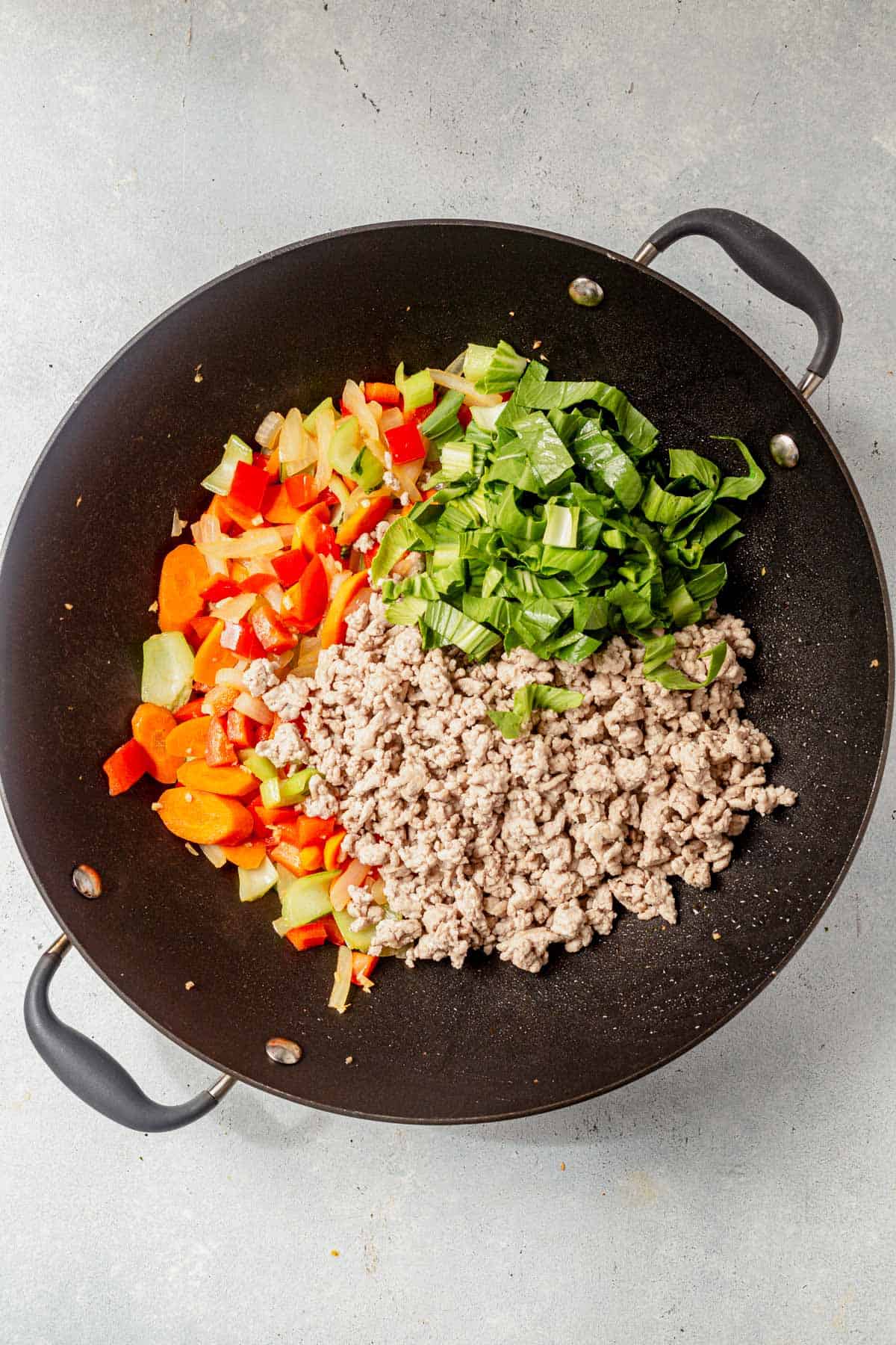 ground pork and stir fry vegetables in a wok.