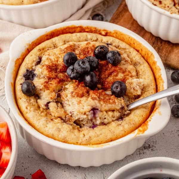 baked protein pancake bowl in a ramekin with cinnamon and blueberries on top.