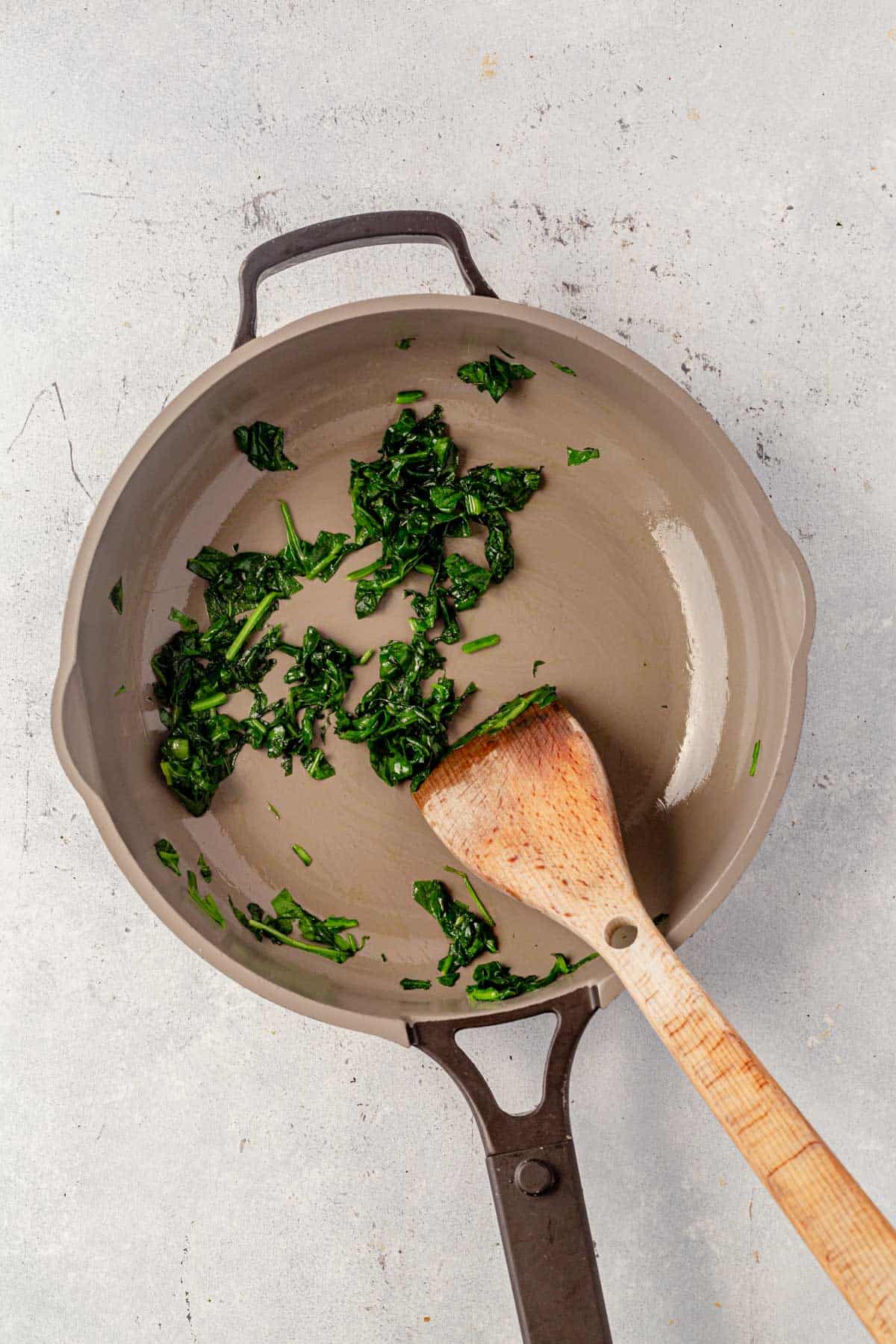 Cooked spinach in a skillet with a spatula.