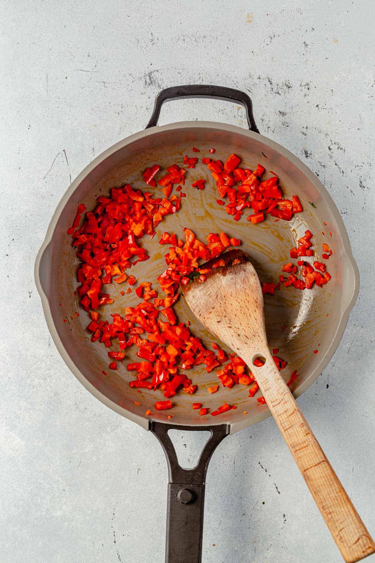 cooked red bell peppers in a skillet with a spatula.