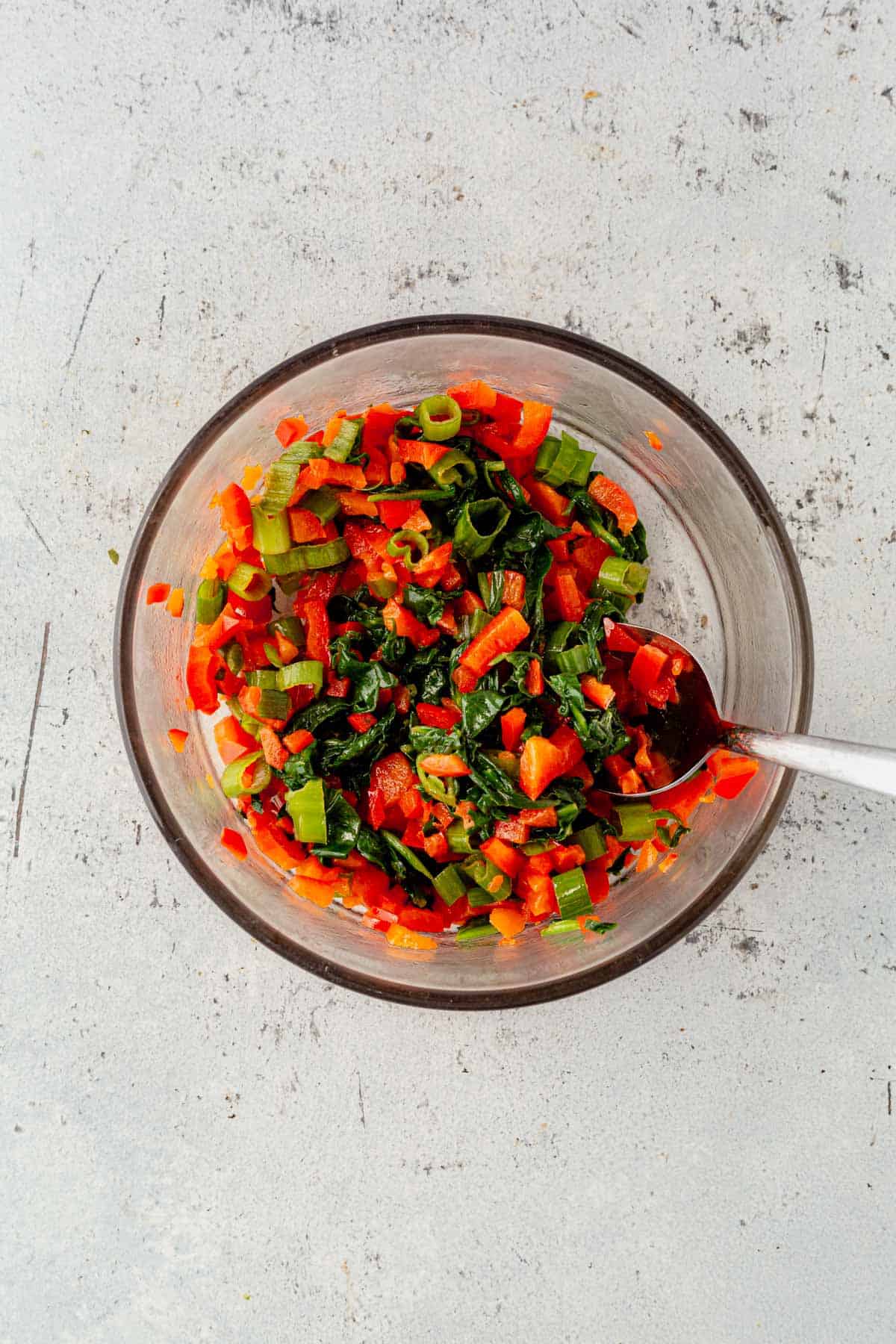 cooked diced peppers, spinach, and green onions in a mixing bowl.