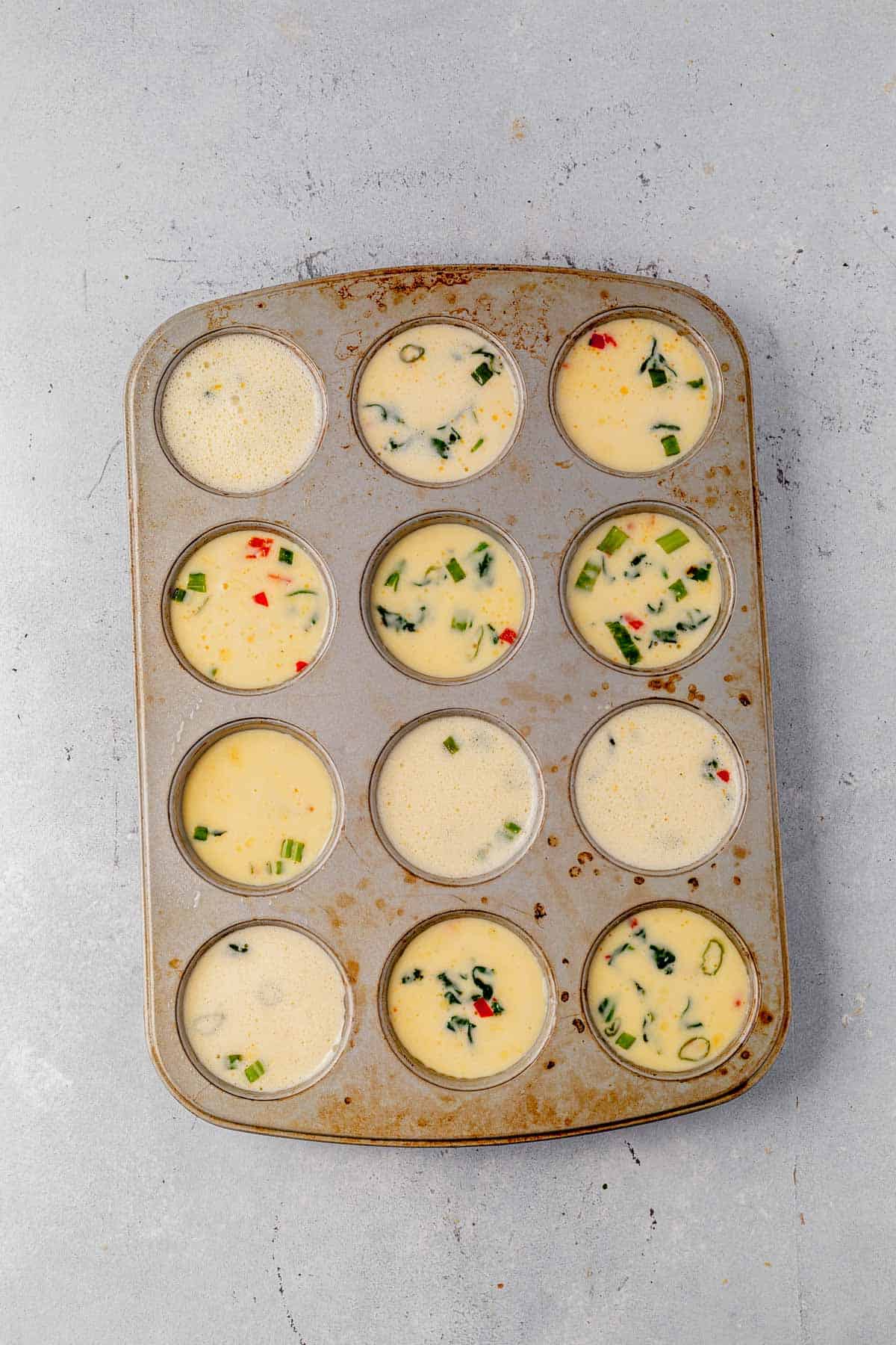 uncooked cottage cheese eggs bites in a muffin tin.