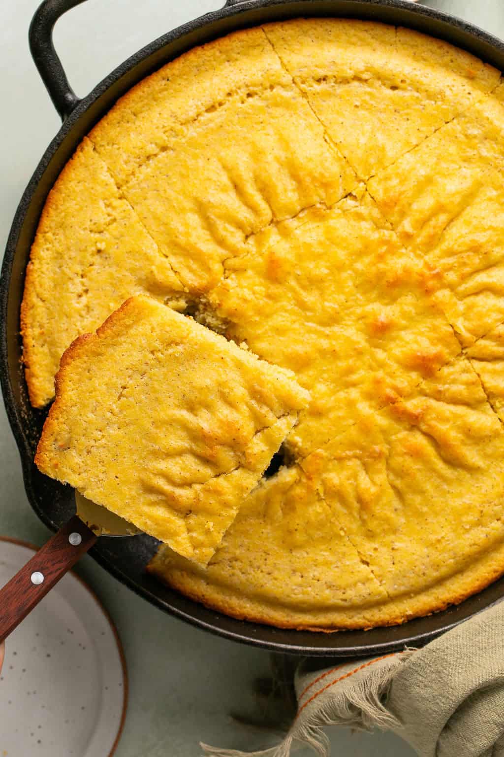 pulling a piece of gluten free cornbread stuffing from a cast iron skillet.