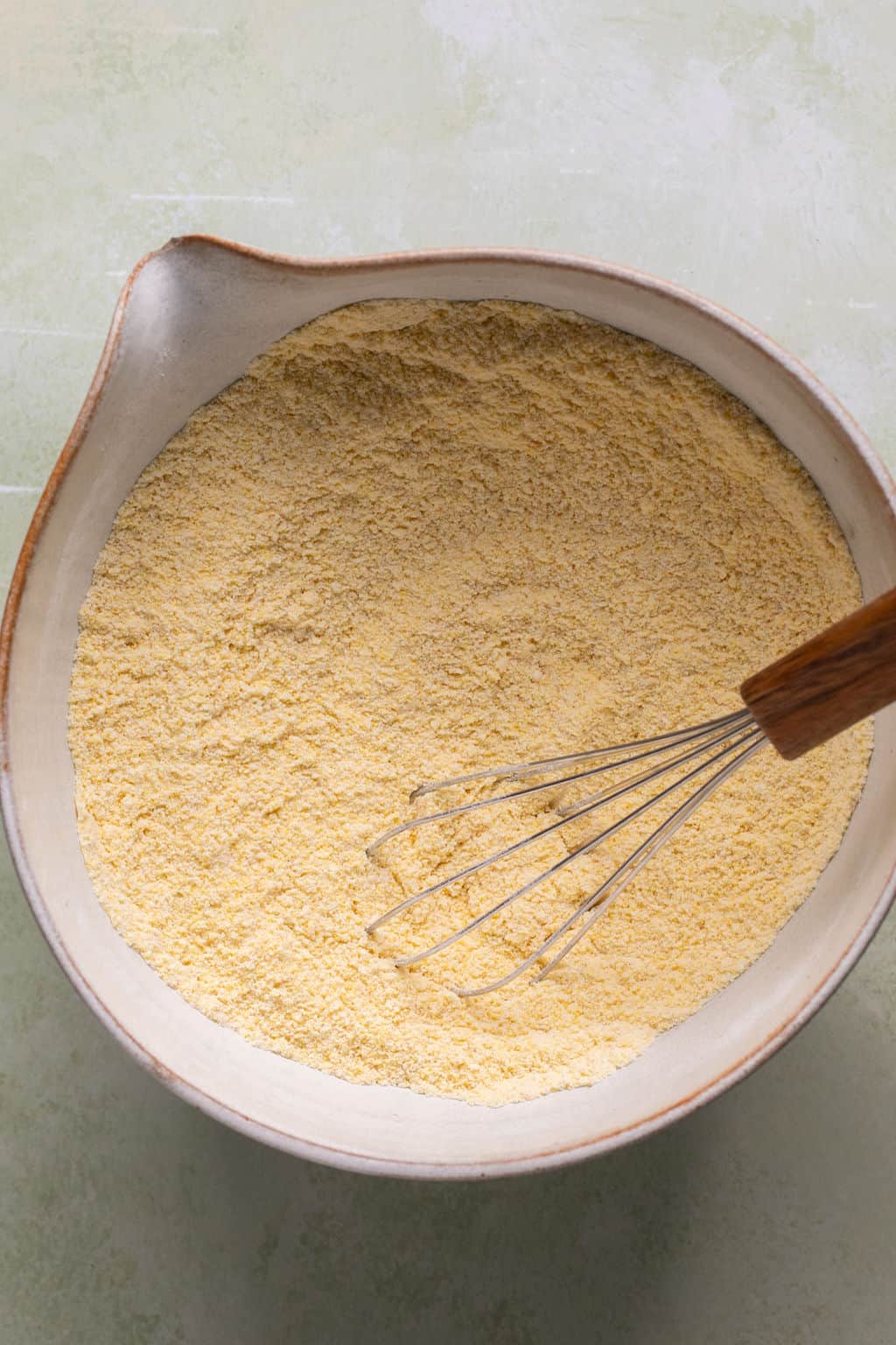 gluten free cornbread dry ingredients in a mixing bowl with a whisk.