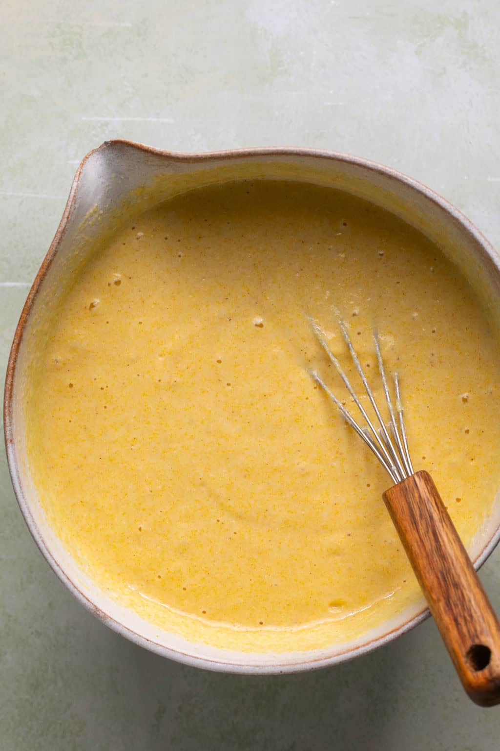 Gluten-free cornbread batter in a mixing bowl with a whisk.