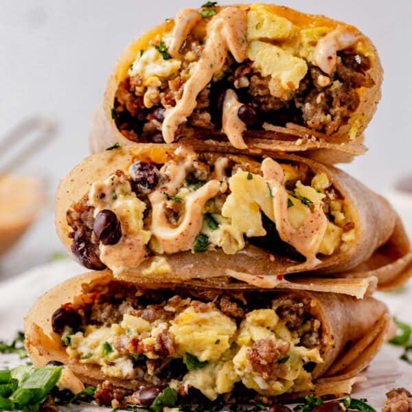 a stack of high protein breakfast burritos with chipotle mayo drizzled on top.