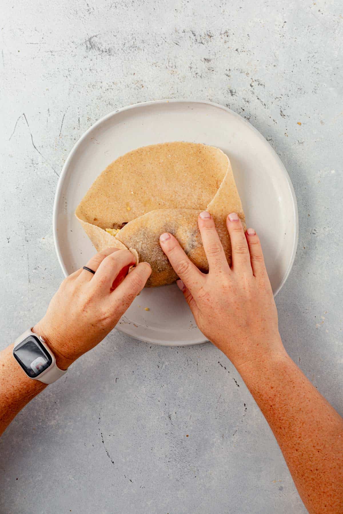 folding a breakfast burrito on a plate.